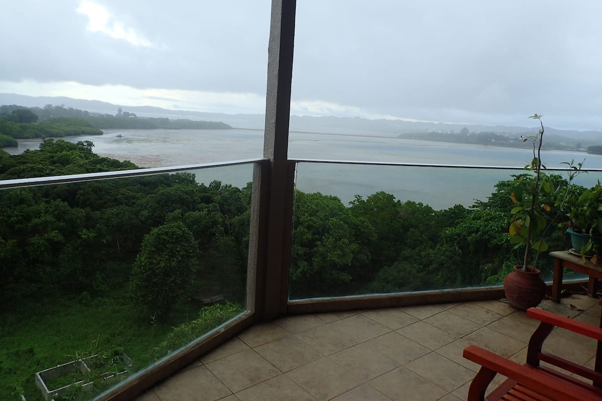 Un balcón con vistas a un río y follaje.