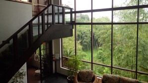 A room with a large window, a staircase, and two patterned chairs. - Cliffside View Hotel (Meyungs)
