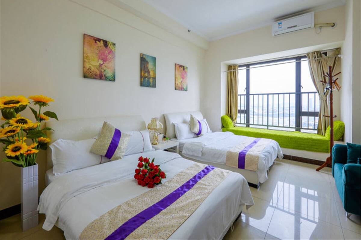 Habitación de hotel con dos camas, un ventanal con vistas y un balcón.
