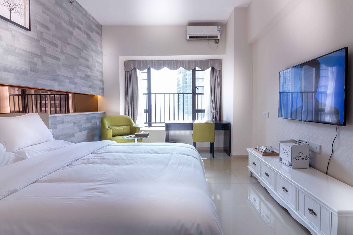 Una habitación de hotel con una cama grande, un escritorio, una silla, un televisor y un armario.