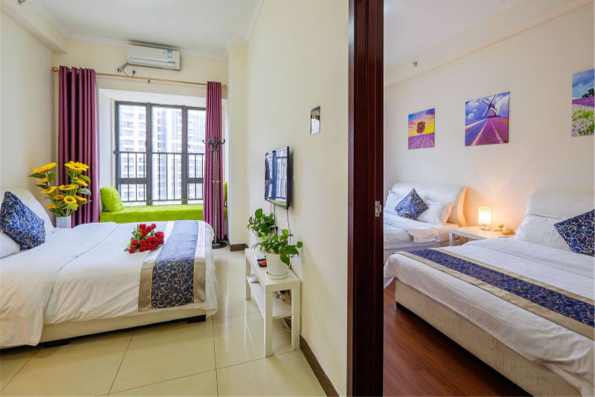 Una habitación de hotel con dos camas, una ventana con cortinas, un televisor de pantalla plana y obras de arte en la pared.