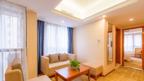 A hotel room with a sofa, a coffee table, and a bed. - Guilin Manhattan Hotel North Station (Guilin)