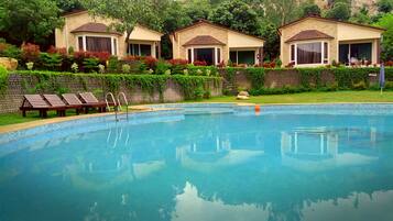 A swimming pool with lounge chairs and a brick wall with greenery.