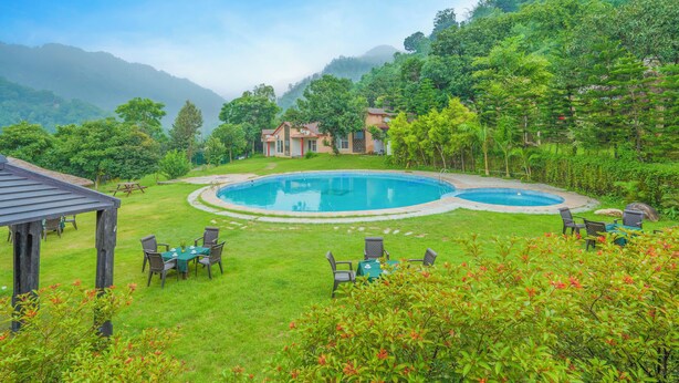 Una piscina rodeada de vegetación exuberante y montañas al fondo.
