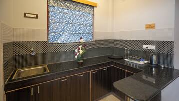 Una cocina con armarios de madera oscura, una encimera negra, un lavamanos de acero inoxidable y un ventanal con vidrio de diseño azul.