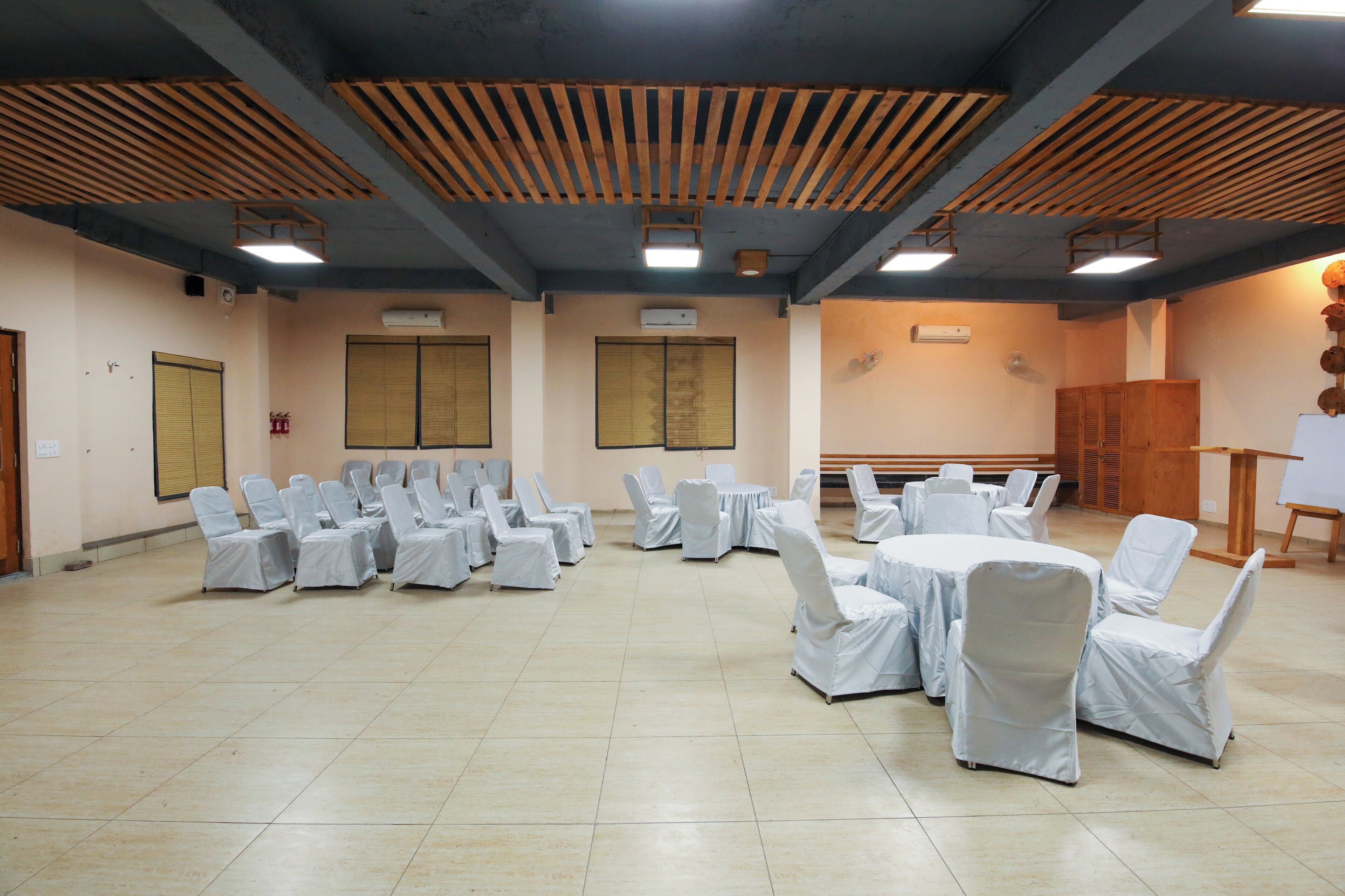 A conference room with rows of chairs and tables, wooden ceiling beams, and a whiteboard.