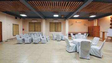 A conference room with rows of chairs and tables, wooden ceiling beams, and a whiteboard.