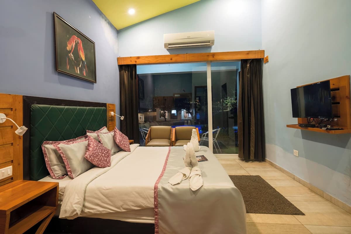 A hotel room with a bed, a desk, a television, and a large window.