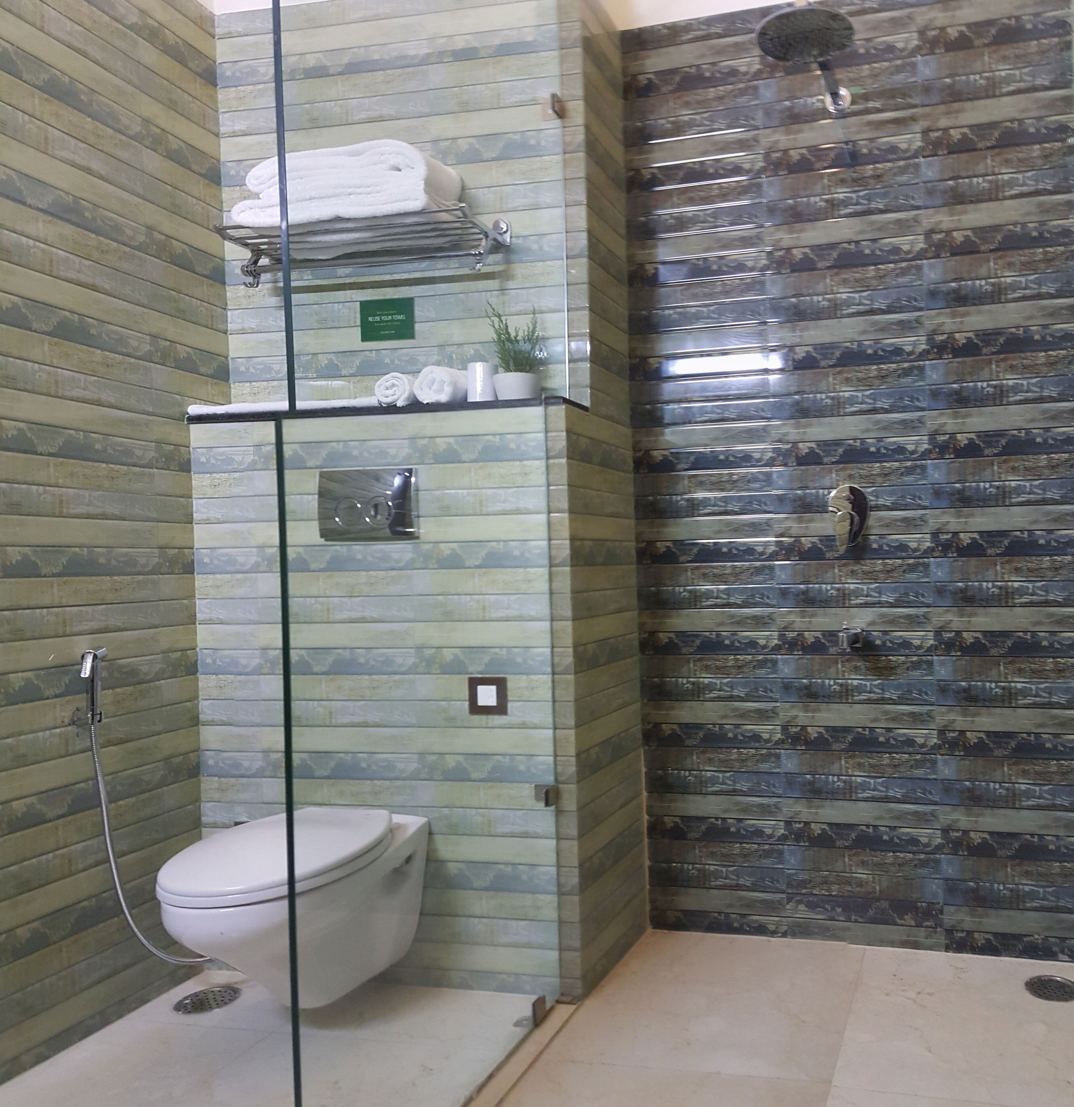 Un baño con cabina de ducha de vidrio, inodoro y un perchero con toallas.