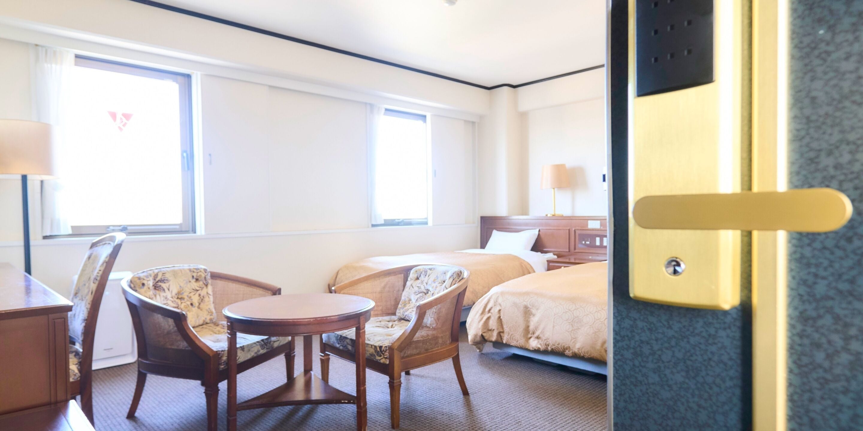 A hotel room with two beds, a small round table, and two chairs.