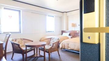 A hotel room with two beds, a small round table, and two chairs.