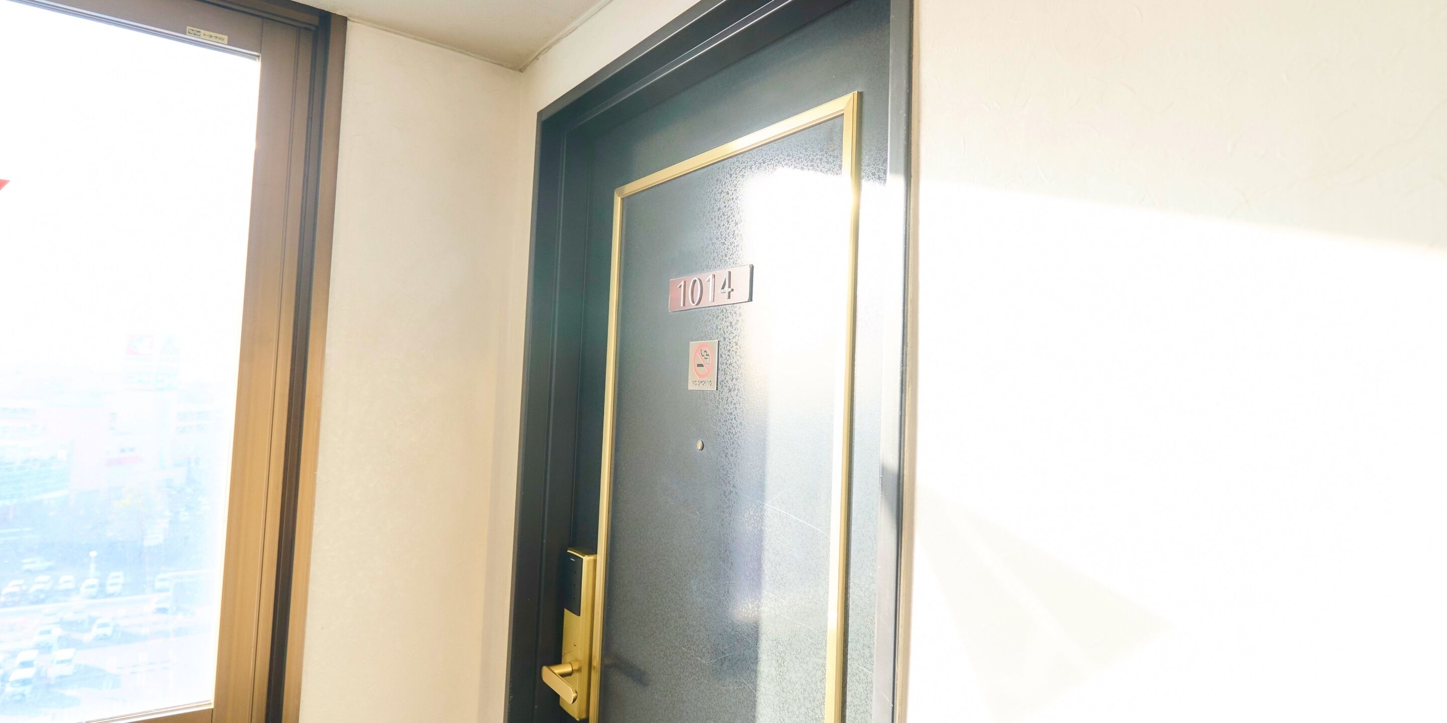 Uma porta com placa de número, uma janela e um puxador.