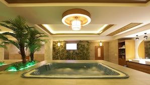Ein Wellnessbereich mit Whirlpool, Palmen und einer Deckenleuchte.