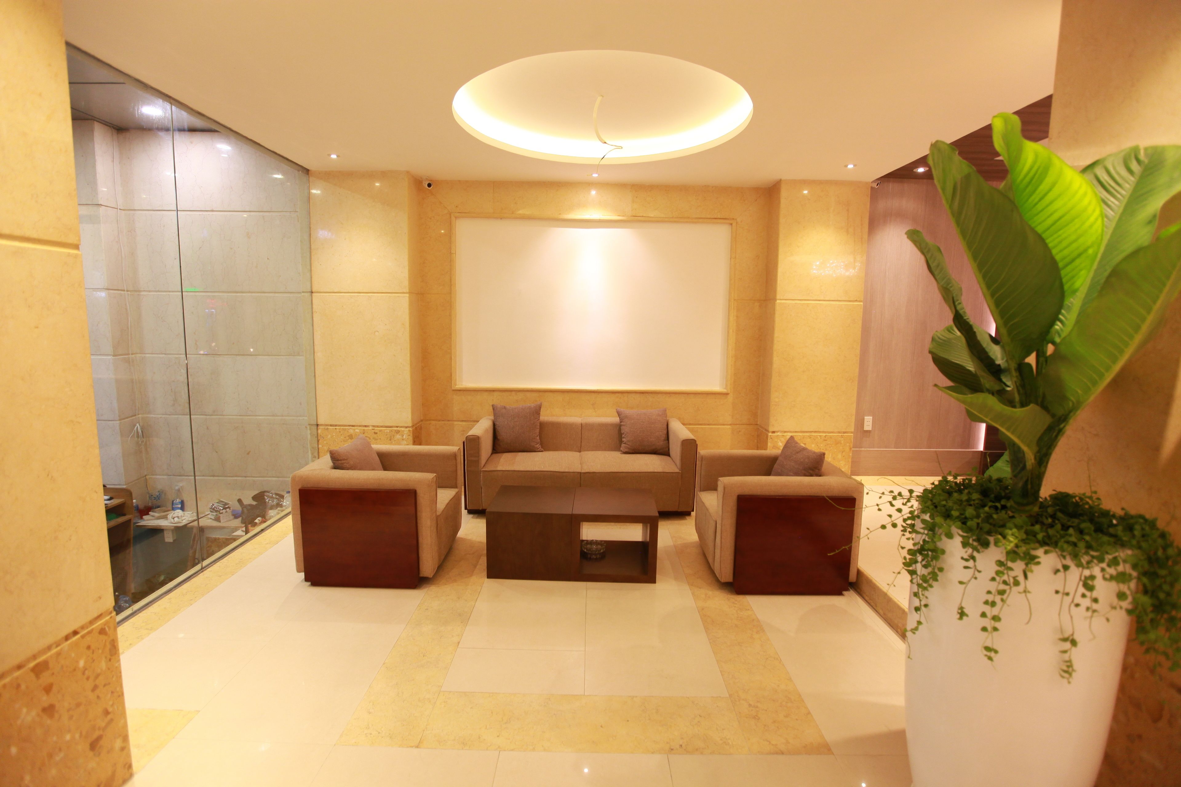 A modern lobby with a beige sofa set, a coffee table, and a large potted plant.