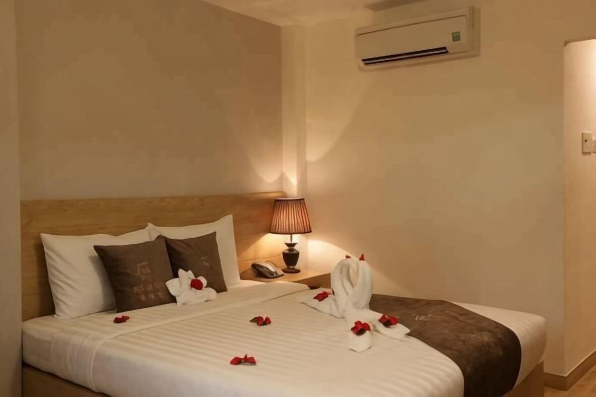 A hotel room with a bed, pillows, a bedside lamp, a phone, and a robe on the bed.