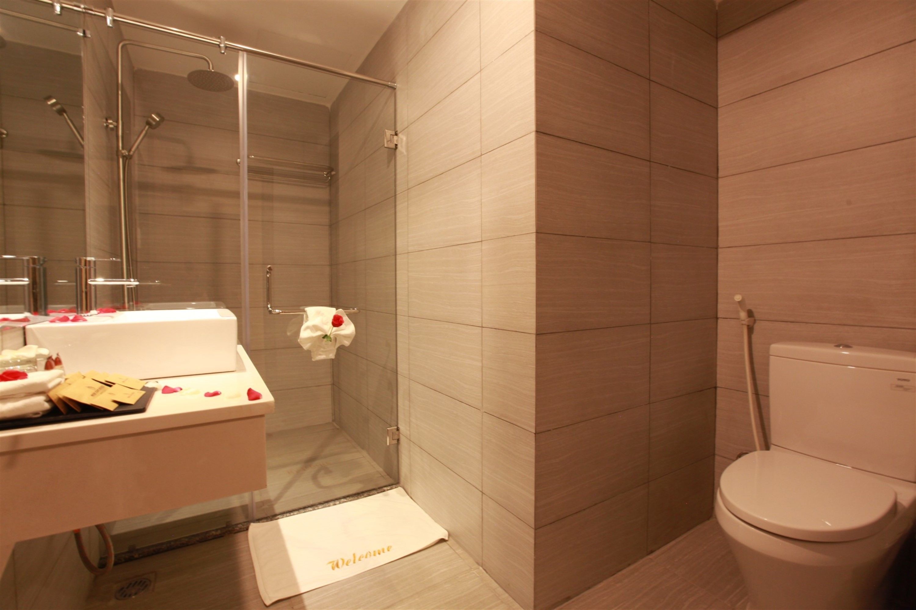 A modern bathroom with a glass-enclosed shower, a white bathtub, and a toilet.