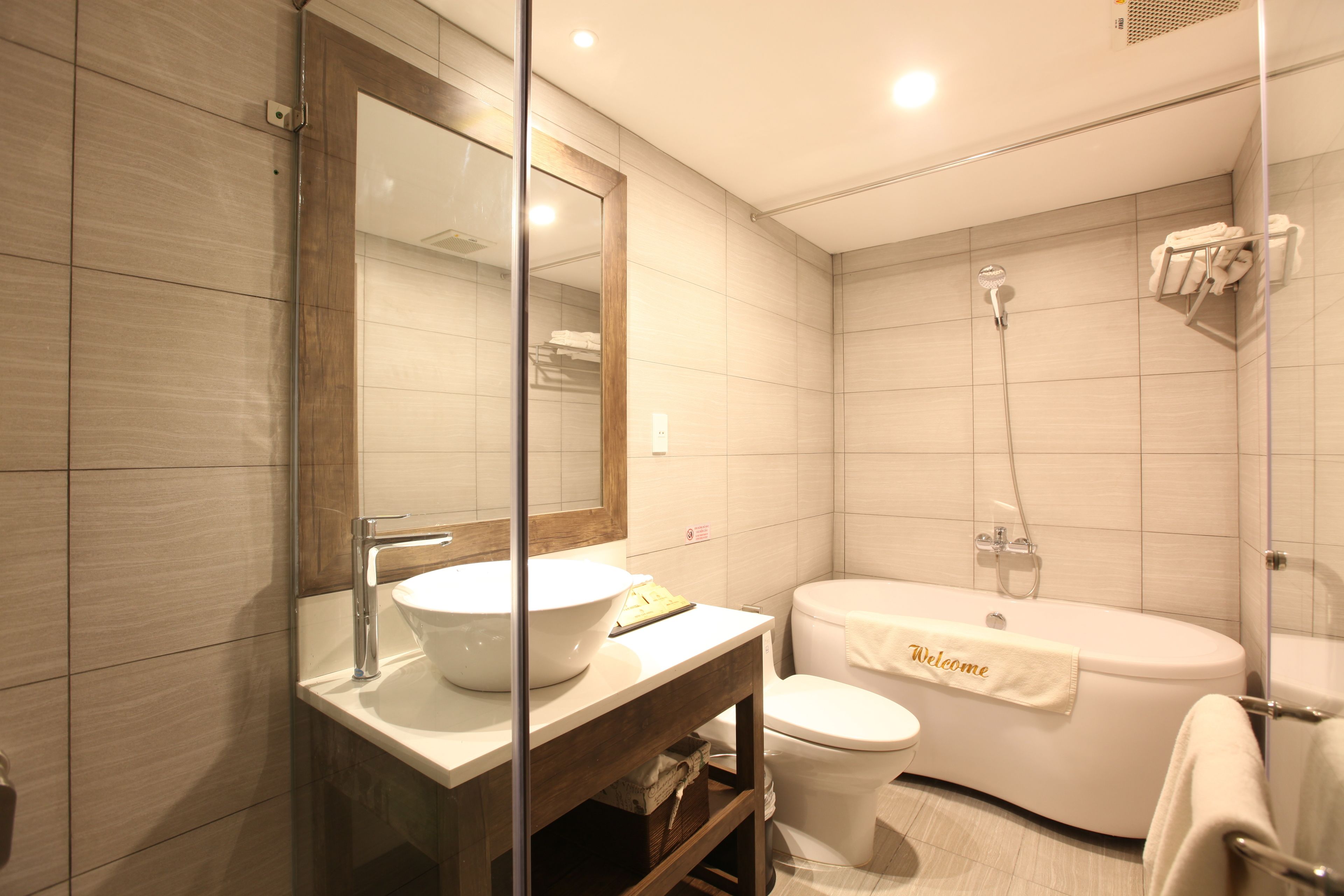 A modern bathroom with a large mirror, a sink, a toilet, and a bathtub.