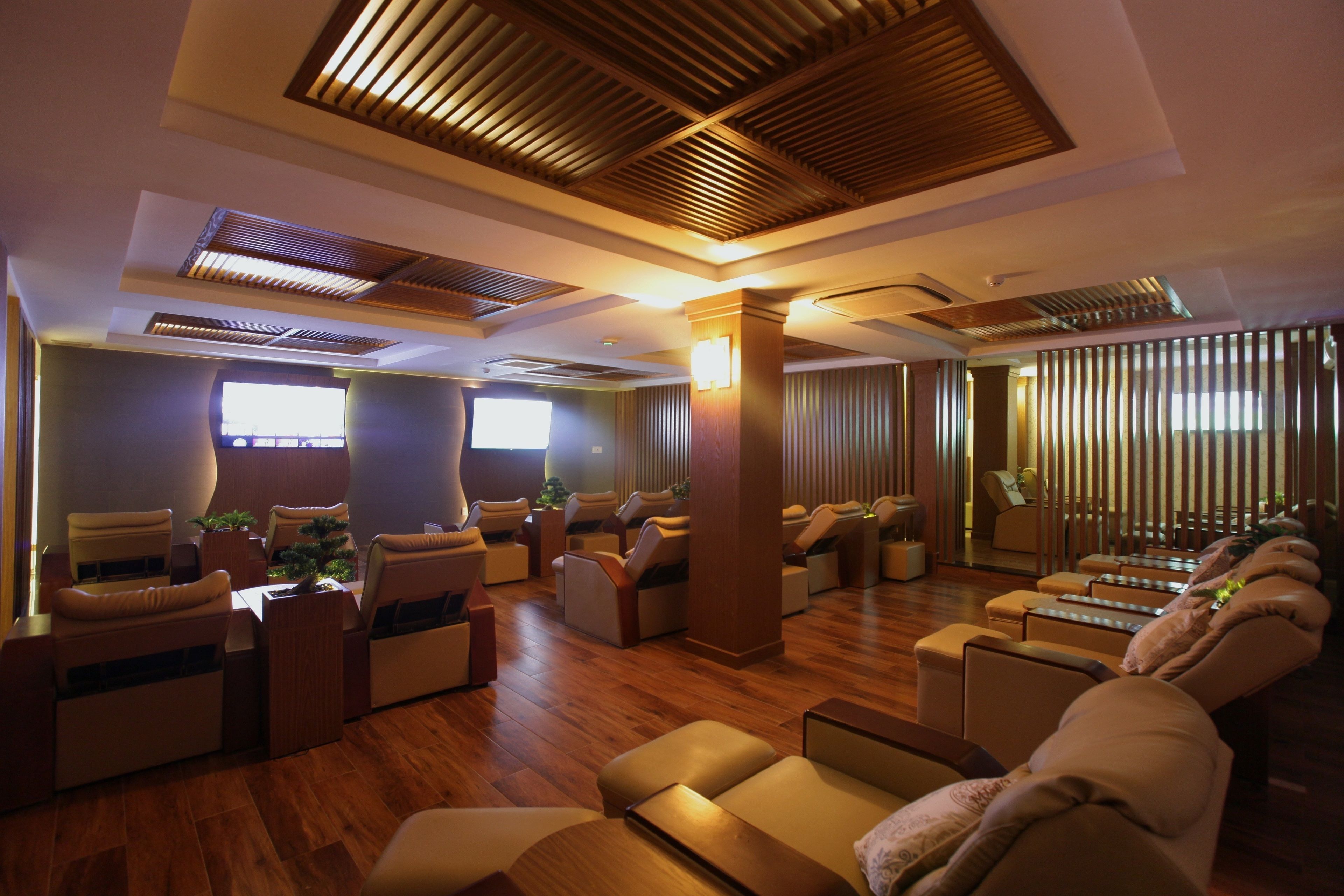 A spa room with massage chairs, wooden flooring, and a large window.