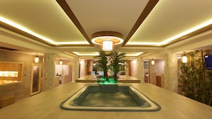 Eine großzügige Lobby mit zentralem Pool, Holzbalkendecke und stimmungsvoller Beleuchtung.