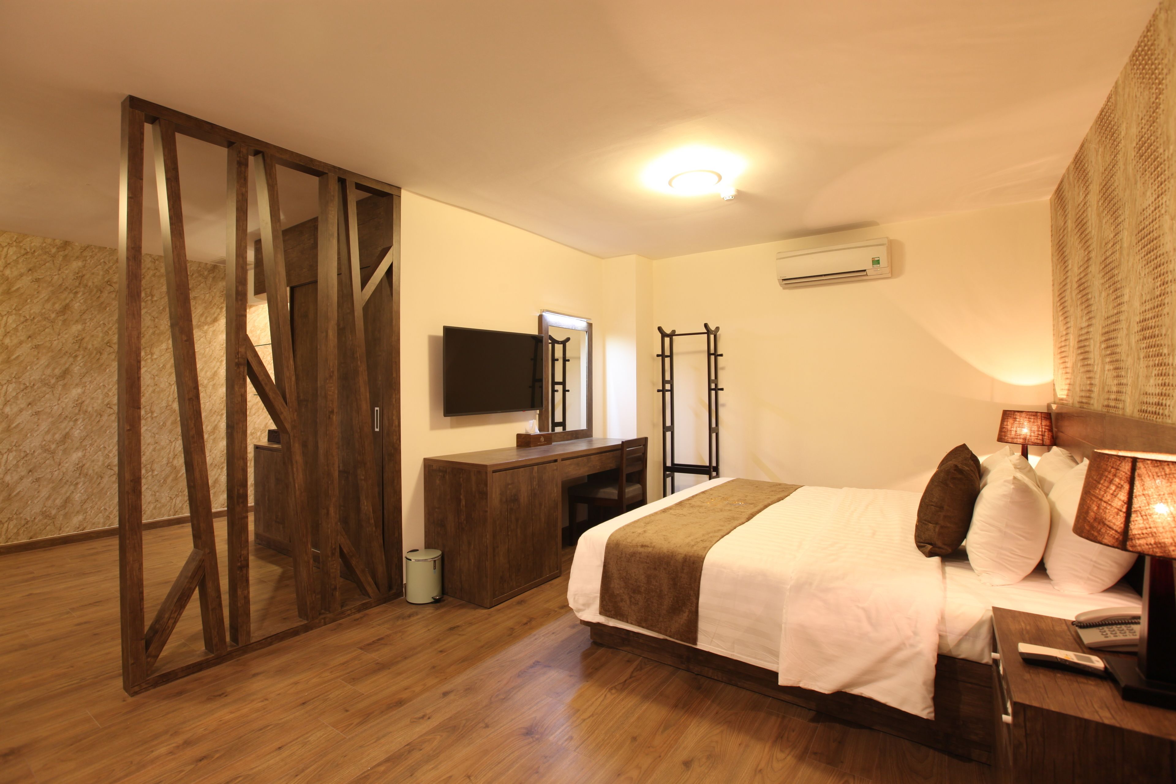 Un dormitorio con cama, mesita de noche, lámpara, televisor y armario de madera.