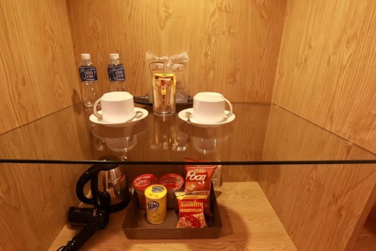 Un interior de madera con una mesa de vidrio que sostiene tazas, una botella y alimentos.