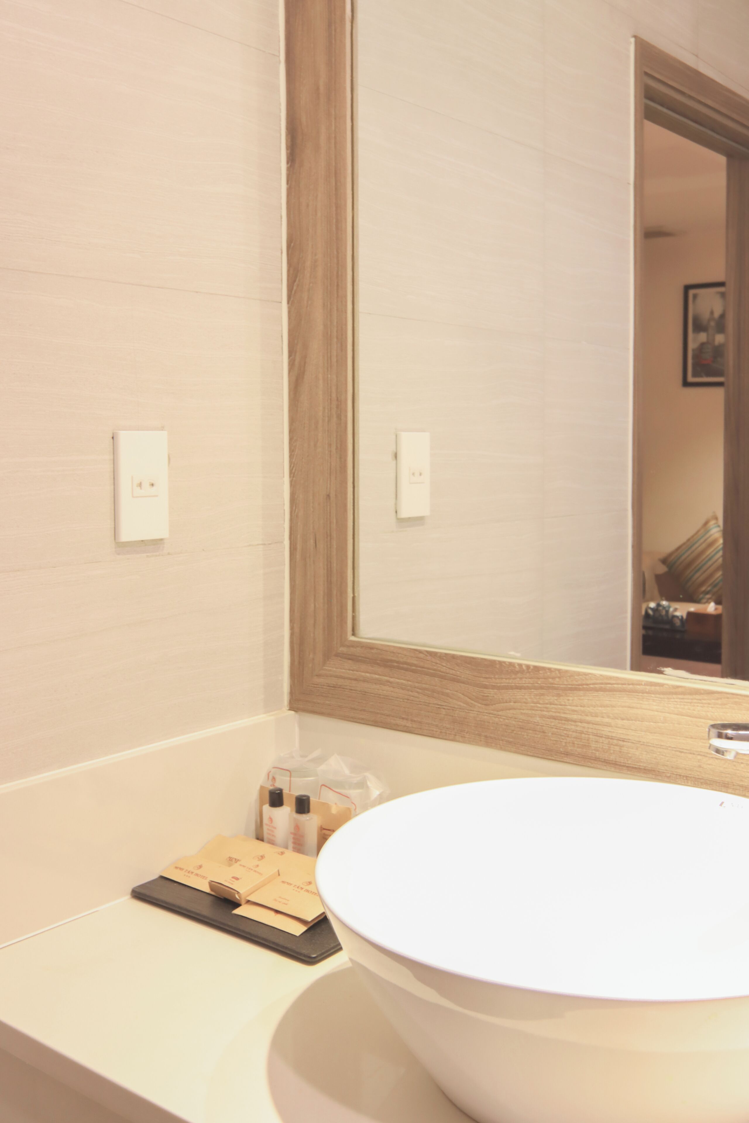 A bathroom with a white sink, a mirror, and a wooden-framed mirror.