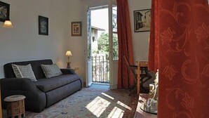 Una sala de estar con un sofá, una mesita redonda, una lámpara y vistas a un espacio exterior a través de una puerta.