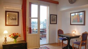 Una habitación con una mesa de comedor, sillas, un jarrón con flores y cuadros en las paredes.