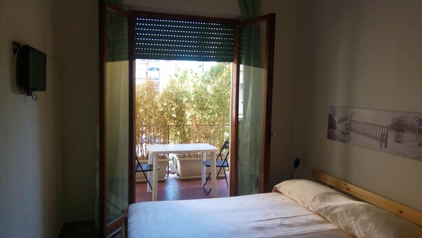 A bedroom with a bed, a small table, and a chair outside a bamboo screen door. - LovelyBed (Aprilia)