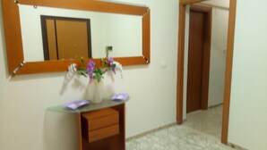 A bathroom with a mirror, a sink, and a vase with flowers. - LovelyBed (Aprilia)