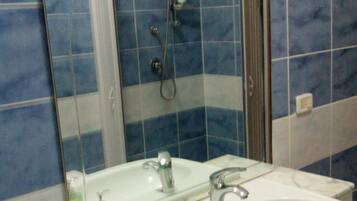 A bathroom with a large mirror, two sinks, and a shower.