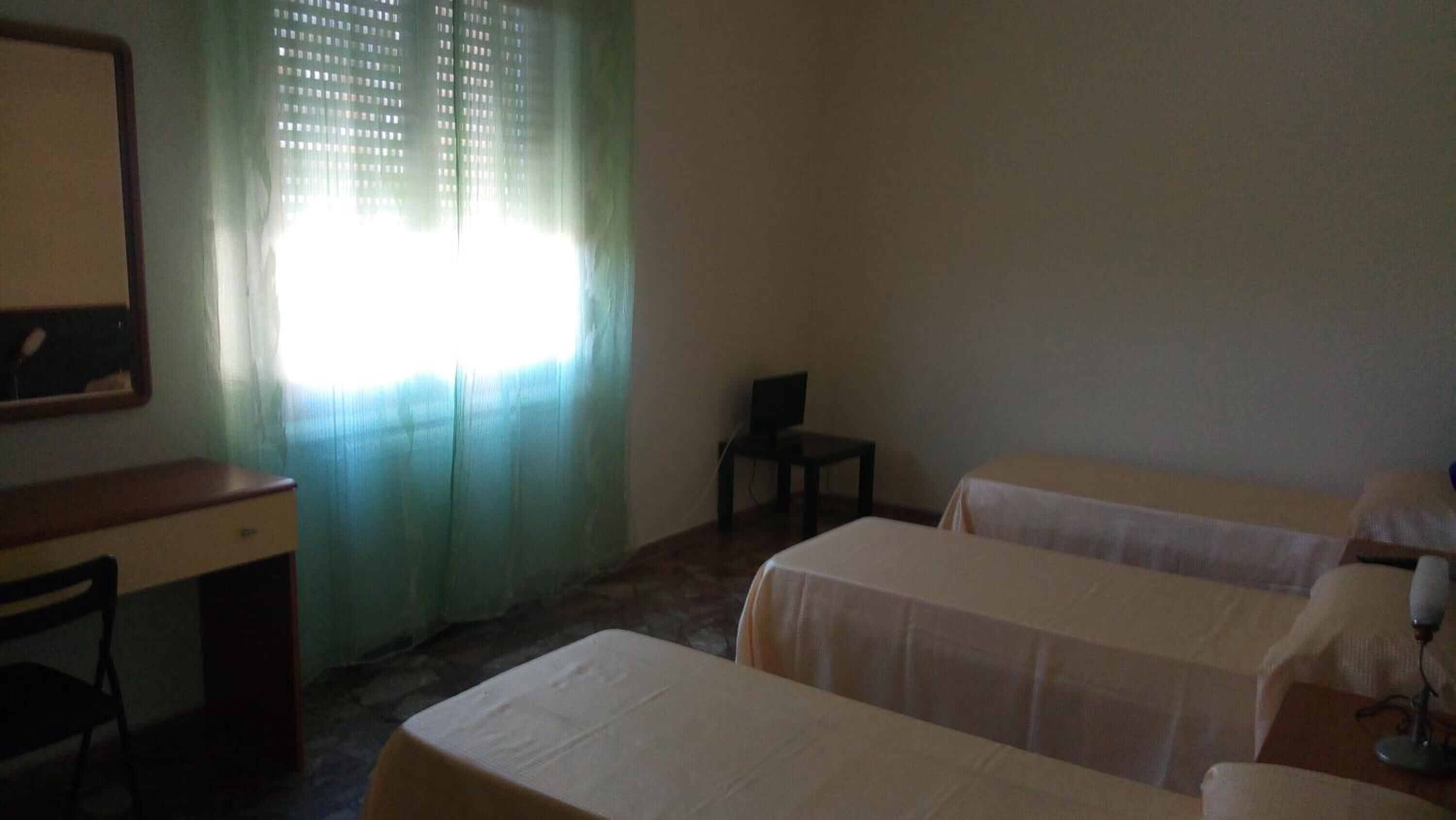 A room with two beds, a desk, and a chair.
