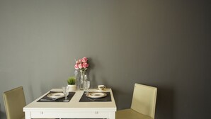 A dining table set with plates, cutlery, and a vase of flowers. - Heyha Hotel (Bangkok)