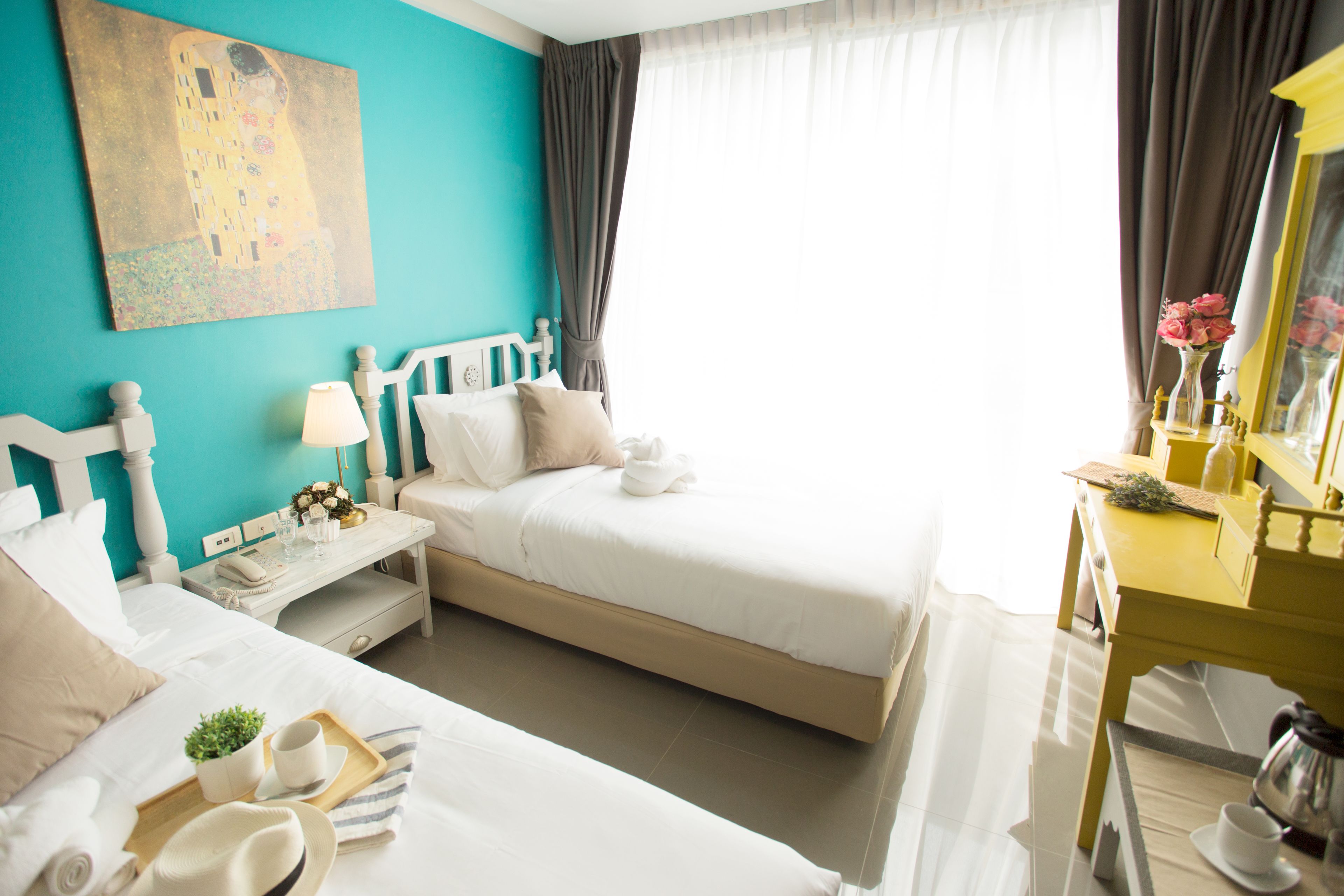 A hotel room with two beds, a desk, a chair, a mirror, and a painting on the wall.