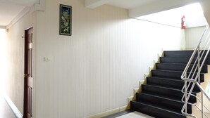 Una escalera con escalones negros y una barandilla de metal que conduce a un piso superior.