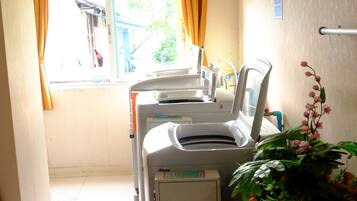 A clinical room with medical equipment, a window with curtains, and a potted plant.