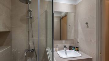Un baño moderno con ducha de vidrio, lavabo con espejo y retrete.