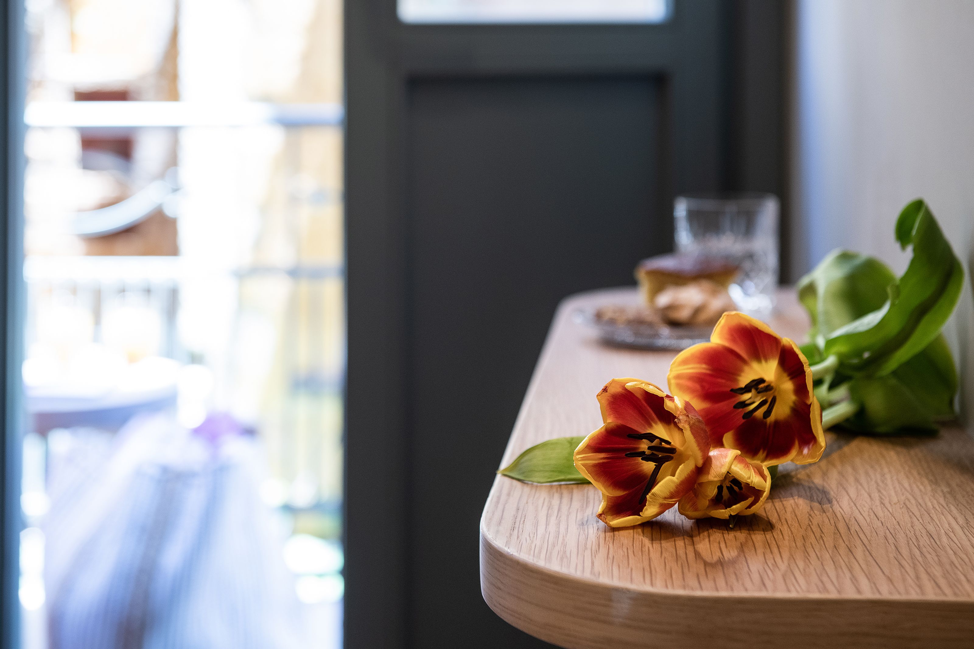 A wooden table with tulips and a glass of water.