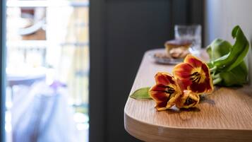 A wooden table with tulips and a glass of water.