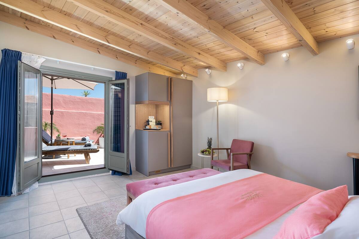 Une chambre à coucher avec un lit, un bureau, une chaise et une vue sur l’extérieur.