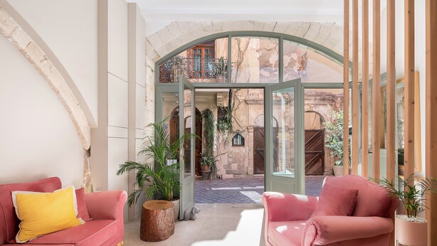 A spacious living area with a pink sofa, a wooden coffee table, and a potted plant. - Viaggio Elegant Rooms (Chania)