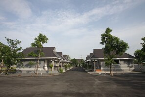 A row of two-story houses with a central driveway, surrounded by trees and a clear sky. - Rongsang Resort (Nong Khae)