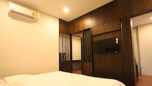 A bedroom with a bed, an air conditioning unit, a wooden wardrobe, and a mirror. - Rongsang Resort (Nong Khae)