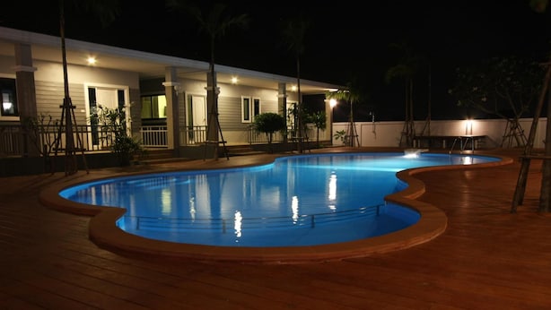 A swimming pool with a wooden deck, surrounded by a house with a covered porch and potted plants. - Rongsang Resort (Nong Khae)