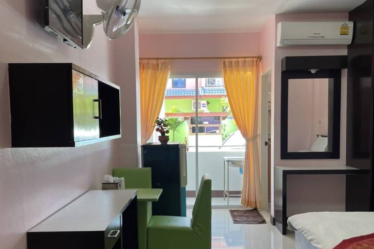 A modern hotel room with a bed, a desk, a chair, a TV, and a window with curtains.