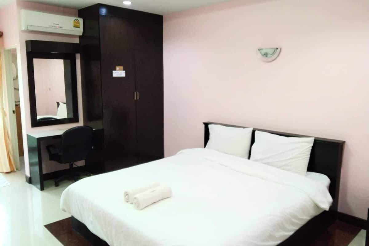 A hotel room with a bed, a desk, a wardrobe, and a mirror.