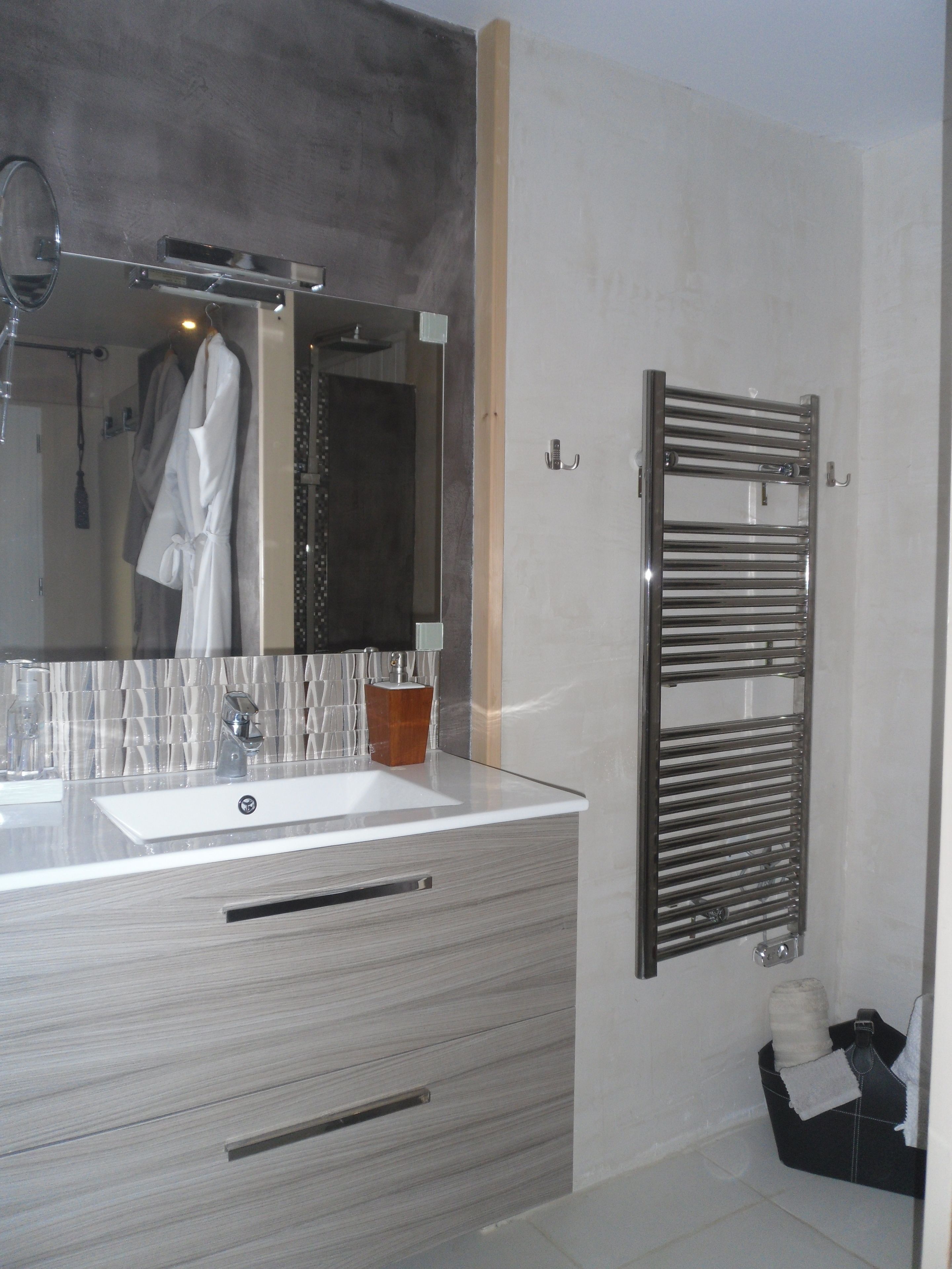 A modern bathroom with a large mirror, a sink, and a towel rack.