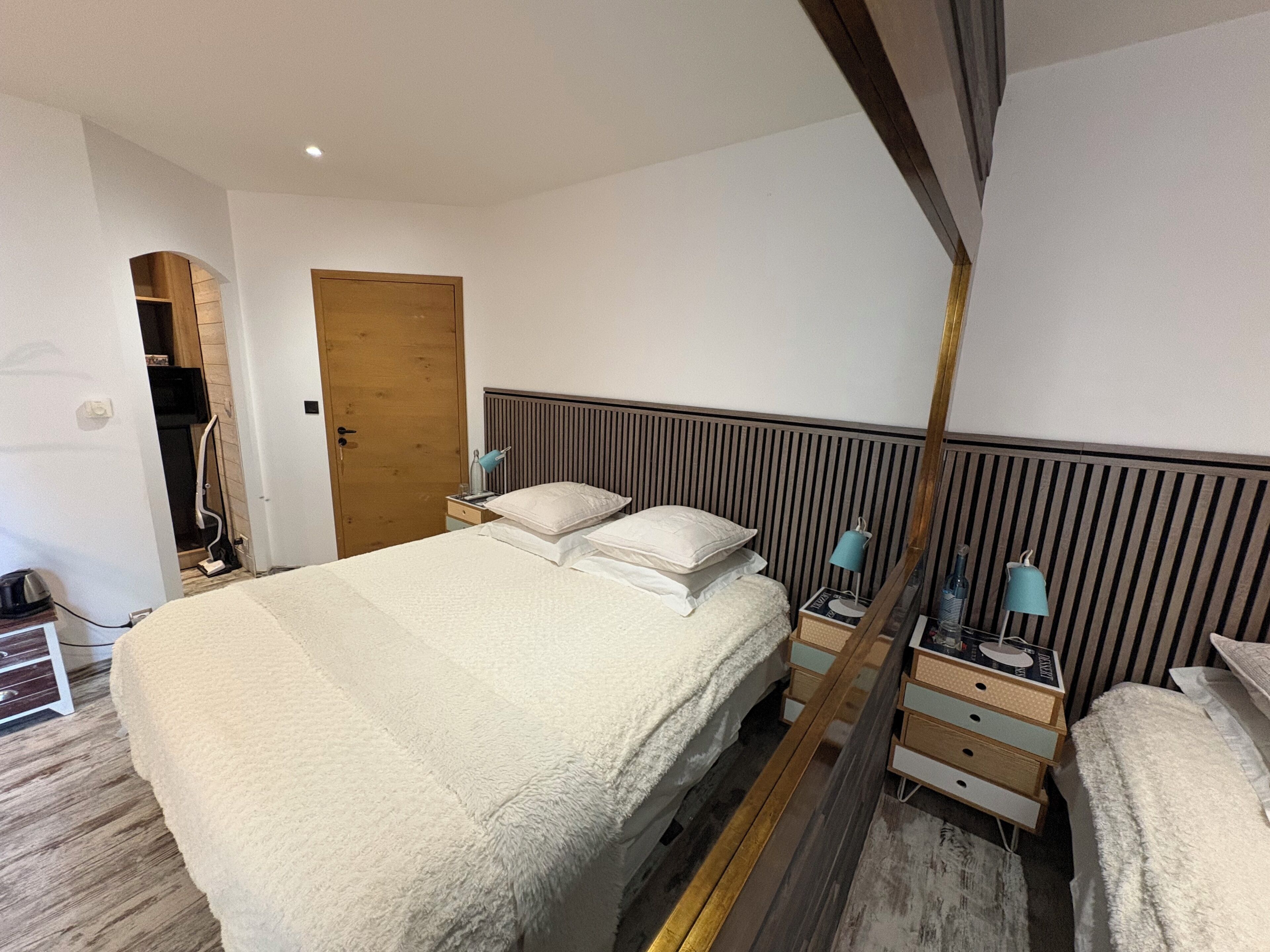 Une chambre moderne avec un grand lit, des tables de chevet avec des lampes et une porte en bois.