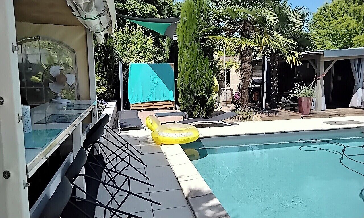 A swimming pool with a yellow inflatable ring, a covered seating area, and a potted plant.