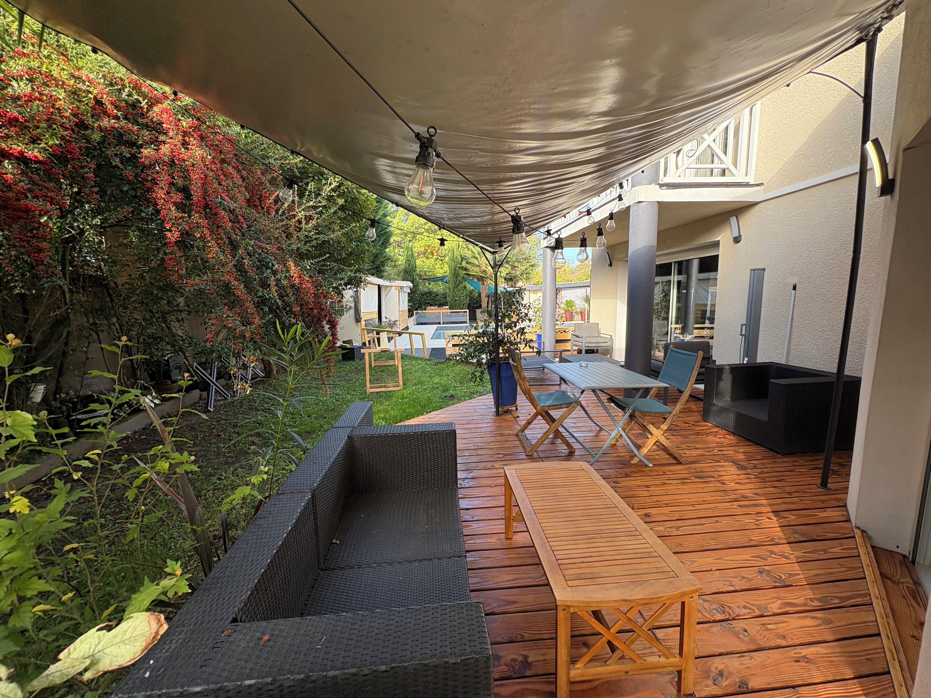 Een buitenpatio met een houten terras, een ingebouwde plantenbak en een tafel met stoelen.